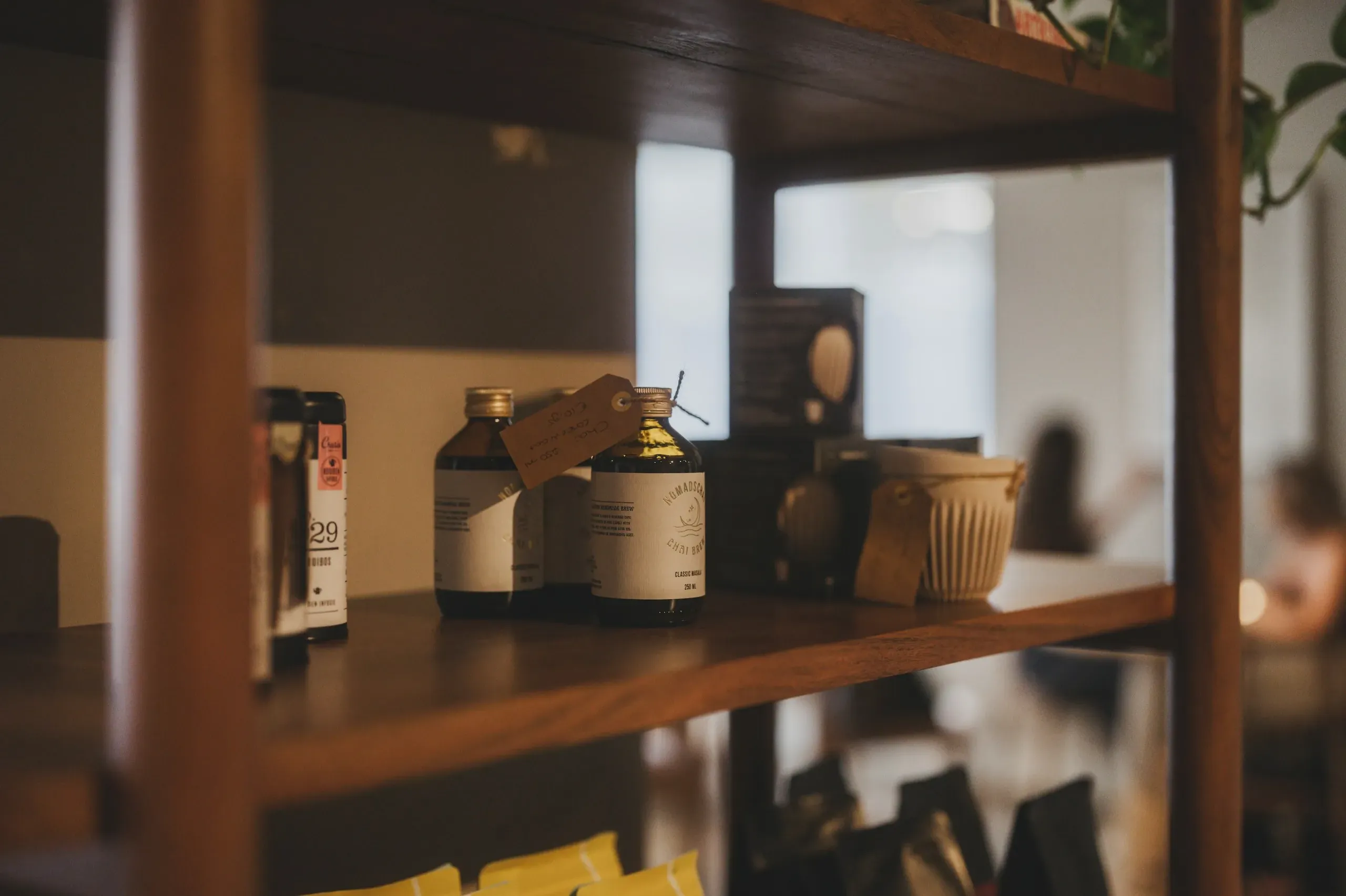 Rafturi de lemn într-un magazin mic, cu sticle etichetate și pungi de cafea